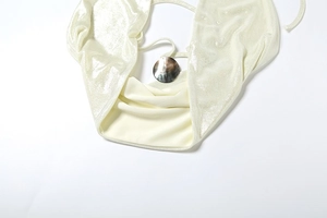 Détail du tissu scintillant et boucle nacrée sur l'ensemble haut dos nu licou beige