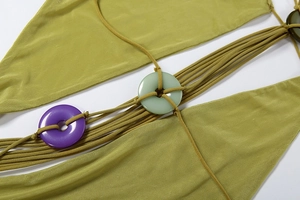Détail de la robe en maille verte avec fines bretelles et anneaux décoratifs colorés