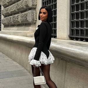 Dettaglio dei polsini in pizzo bianco su un body nero sexy con scollo a V profondo