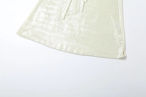 Gros plan sur la texture du tissu métallique vert clair scintillant sur l'ourlet d'un ensemble