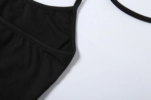 Detailed close-up of black ribbed knit fabric and stitching on a halter crop top