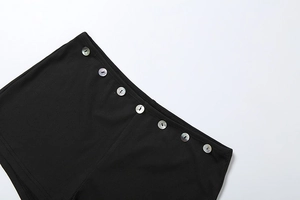 Detail of black ribbed knit shorts with decorative mother-of-pearl buttons on waist