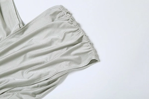 Détail du tissu en soie argentée avec plis raffinés et texture fluide élégante