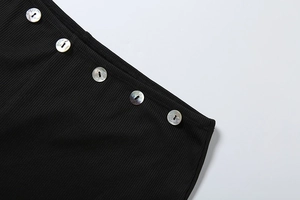 Close-up of black ribbed knit fabric featuring five iridescent pearl-like buttons