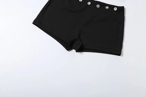 Close-up of black ribbed knit shorts with decorative metallic buttons on the waistline