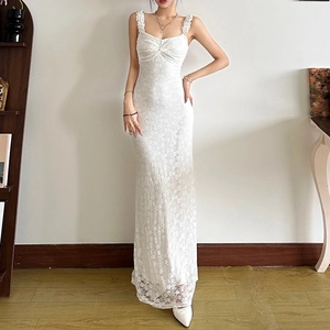 Détail d'une robe longue en dentelle blanche avec fines bretelles et buste froncé