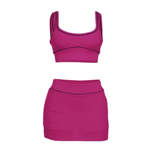 Detailansicht des magentafarbenen Sportsets mit bauchfreiem Top und Minirock mit schwarzem Rand