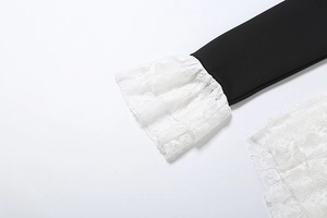 Dettaglio dell'elegante bordo in pizzo bianco a doppio strato su una tuta nera chic