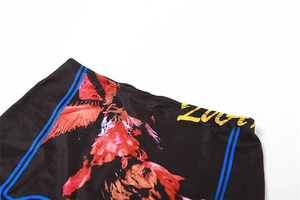 Detail of high-stretch floral fabric with red patterns and yellow Zoot logo print