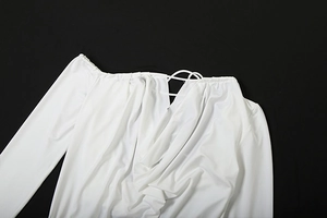 Detail of white off-shoulder dress featuring cross pleated neckline and lace-up design