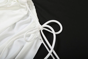 Detail of white satin dress featuring intricate drawstring ties and pleated fabric texture