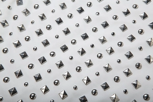 Detailed macro view of white fabric with silver round and gold pyramid studs