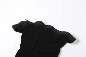 Dettaglio dei pantaloni in rete nera con strisce traforate e bordi ondulati rifiniti