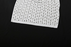 Detailed view of silver square and round metallic studs on a white knitted garment