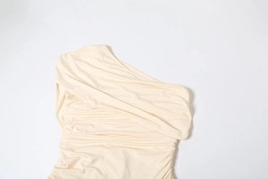 Detail showing the elegant cream ruched texture and one-shoulder neckline of the long dress