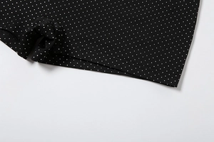 Macro shot of micro polka dot pattern and durable flat-lock stitching on black fabric