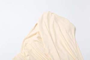 Detailed macro view of beige elegant dress showing smooth elastic fabric and fine edge stitching