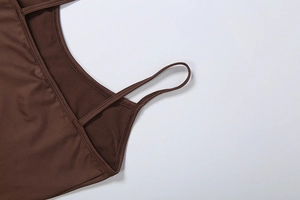 Close-up of fine stitching on the straps and neckline of a dark brown satin slip dress