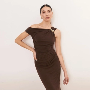 Détail d'une robe froncée marron foncé à une épaule avec ornement en métal doré
