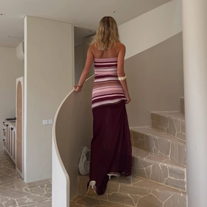 Detail of striped tube top and sheer burgundy mesh skirt set on a model walking on stairs
