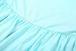 Macro detail of the light blue dress featuring fine twill texture and pleated ruffled stitching