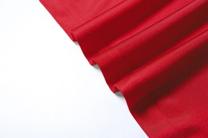 Détail du tissu en maille rouge vif montrant la texture fine et le drapé souple du vêtement