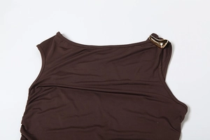 Détail de la robe en tricot marron foncé avec décolleté asymétrique et boucle dorée