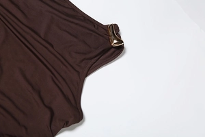 Détail d'une robe en maille marron chocolat avec boucle en métal doré en forme de coeur