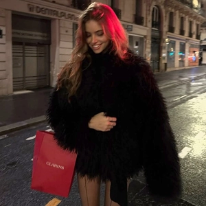 Detailed texture of black long-hair faux fur jacket on a woman in a night street setting
