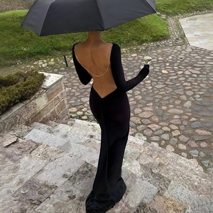 Back detail of a slim-fit backless black maxi dress featuring gold chain decorations