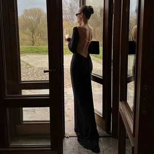 Detail of elegant backless black maxi dress featuring a gold metal chain accent and slim fit