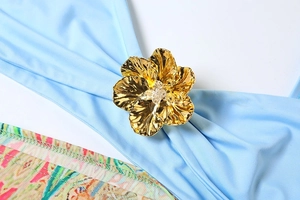 Detail of golden metal flower accessory with sparkling crystals on blue fabric