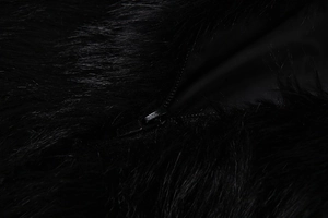 Close-up detail of smooth metal zipper on premium black long-haired faux fur coat