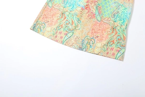 Detail of bohemian paisley print fabric with vibrant colors and precise stitching on the hem