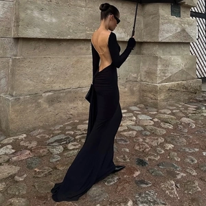 Detailed close-up of open back dress with gold chain ornament and long sleeves
