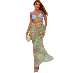 Detail of high-waist paisley maxi skirt with a golden seashell clutch and floral bra top