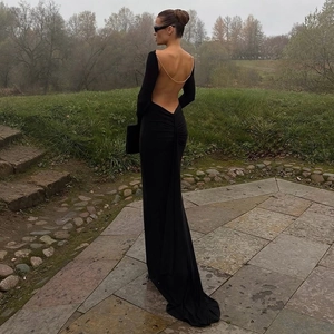 Detailed view of an open back black maxi dress with elegant gold chain decoration