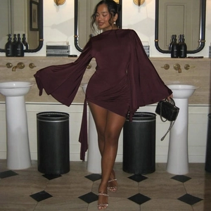 Detail of burgundy bodycon dress featuring oversized bell sleeves and ruched side ties