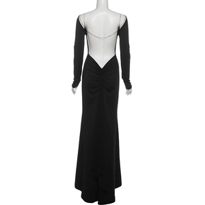 Detail of elegant backless black maxi dress featuring a gold chain across the deep V back