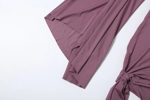 Detail view of smooth deep purple fabric with decorative knot and flared sleeve design