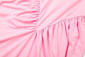 Détail d'une robe rose montrant des plis élégants et la texture fine du tissu en maille