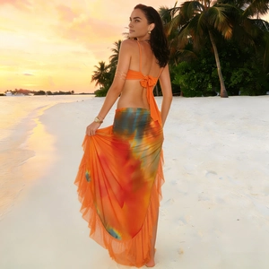 Detail of orange halter top and tie-dye ruffled skirt set in sunset beach scene