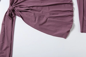 Detailed view of the knotted waist tie and soft knit texture of a mauve jumpsuit