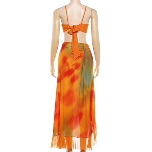 Detail of a vibrant tie-dye maxi skirt and orange crop top with back bow tie design