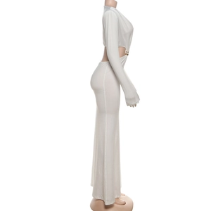 Détail de robe moulante blanche avec boucle métallique dorée et découpes sur le côté