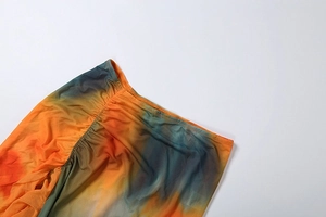 Detail of ruched tie-dye mesh fabric with elastic waistband and orange-blue gradient