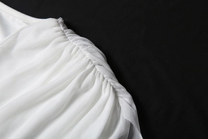 Detailed macro view of delicate white mesh fabric with elegant pleated texture and draping