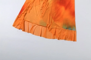Detailed view of the gradient orange and red ruffled hem on lightweight chiffon dress