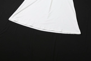 Détail de l'ourlet de la robe blanche montrant la couture à double aiguille et la texture