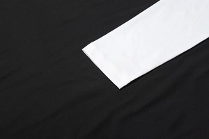 Close-up of contrast white cuffs and stitching on long sleeve mesh dress